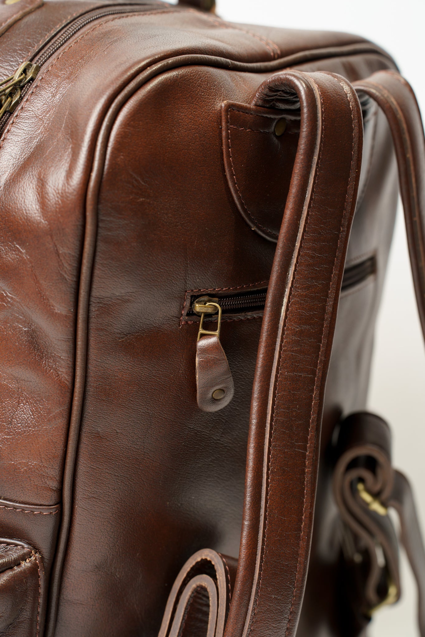 Rear view of Chamra's brown leather backpack with adjustable shoulder straps and a compact compartment fit to hold phones, wallets, passports, or other small items.