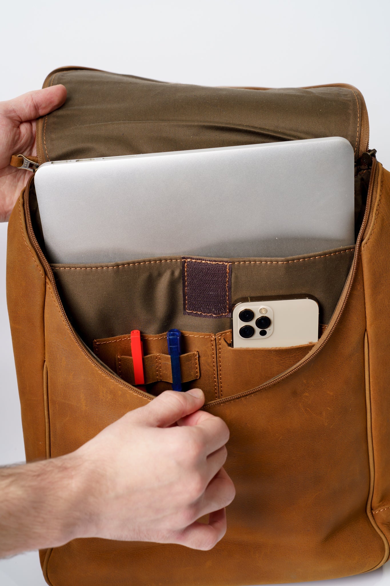 Inner view of Chamra's satchel style backpack. Compartments for laptops, phones, pens, and notebooks can be seen.
