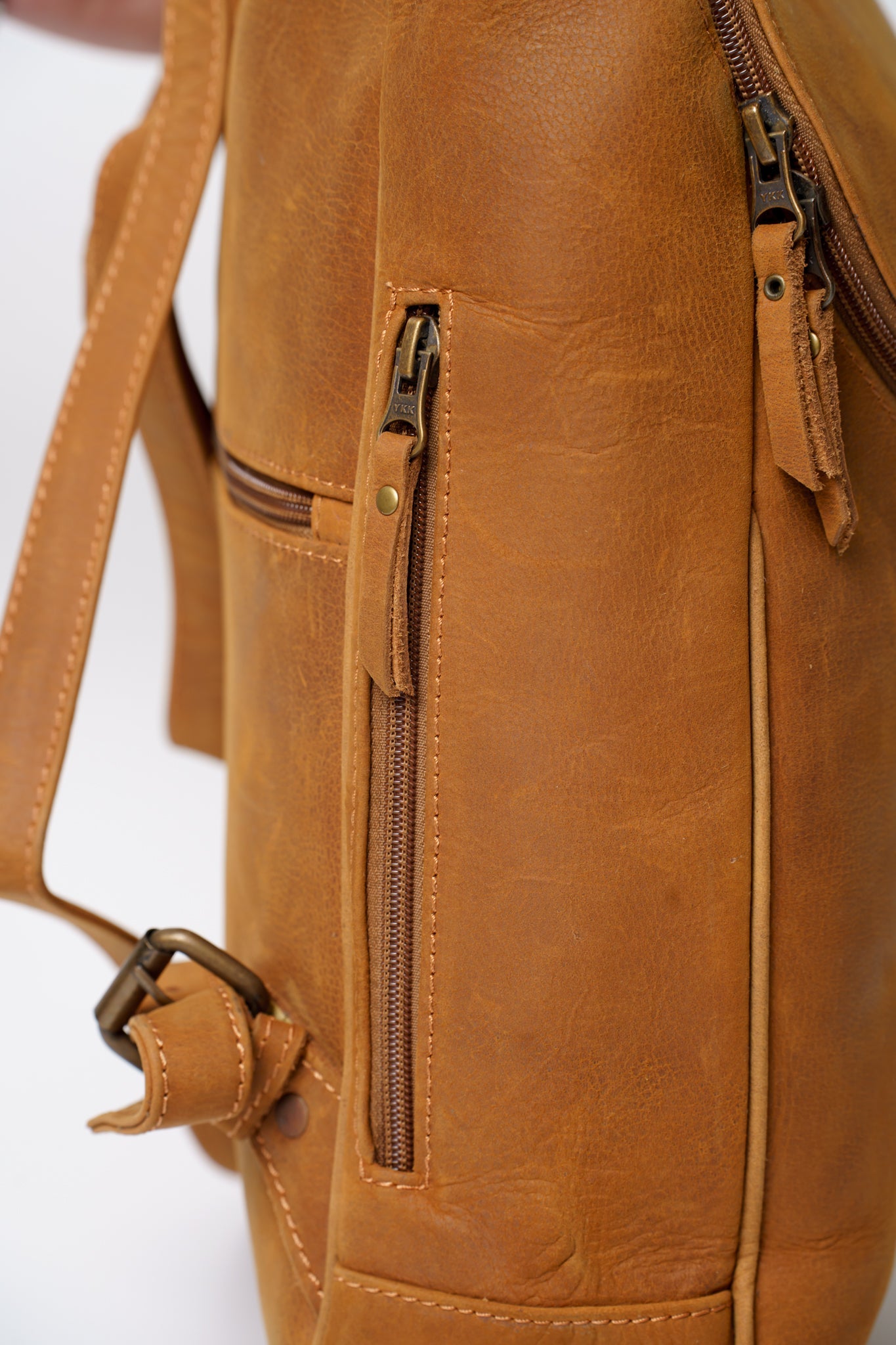 Side view of Chamra's satchel style backpack, showcasing a subtle pocket fit to carry small items like a phone, wallet, passport, or other small items.