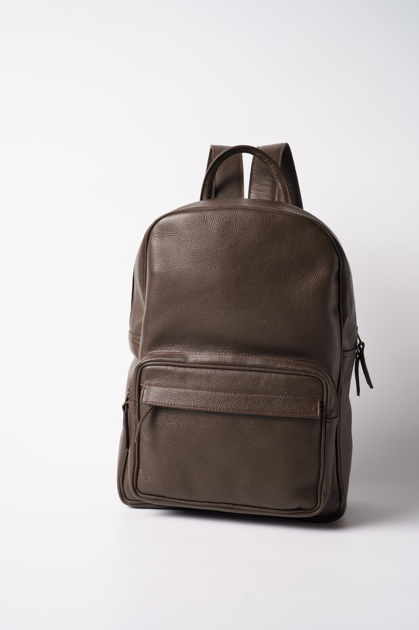 Front view of Chamra's chocolate brown leather bag with a prominent rectangular front pocket near the bottom of the bag. The image also showcases hand carry and shoulder straps.