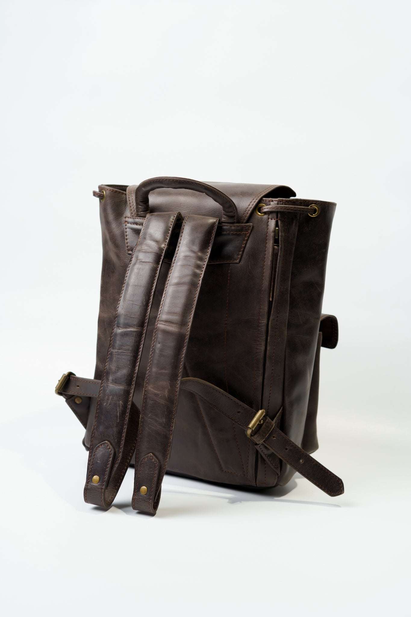Rear view of Chamra's dark brown leather utility backpack showcasing adjustable shoulder straps and a hand-carry strap.