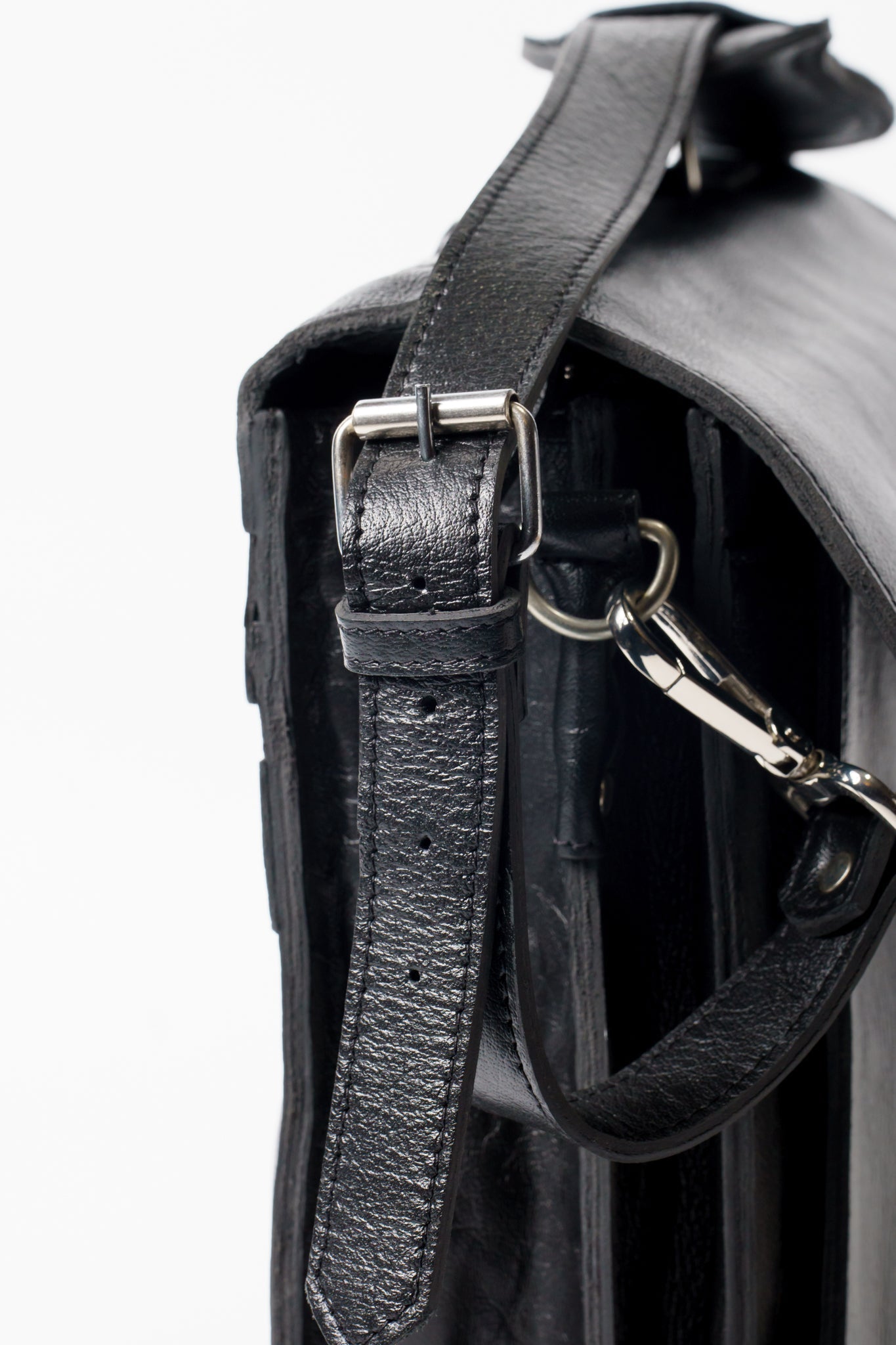 Side view close-up of Chamra's Black leather bag.  The image showcases an adjustable and removable shoulder straps, with brass buckles for long-term use.